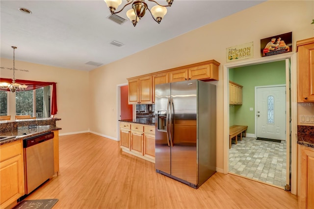 kitchen featuring pendant lighting, appliances with stainless steel finishes, a chandelier, and light wood-type flooring