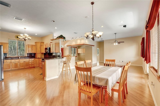 dining area featuring ceiling fan with notable chandelier, sink, and light hardwood / wood-style flooring