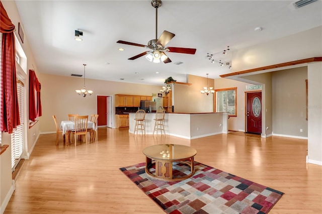 living room featuring ceiling fan with notable chandelier, a healthy amount of sunlight, and light hardwood / wood-style floors