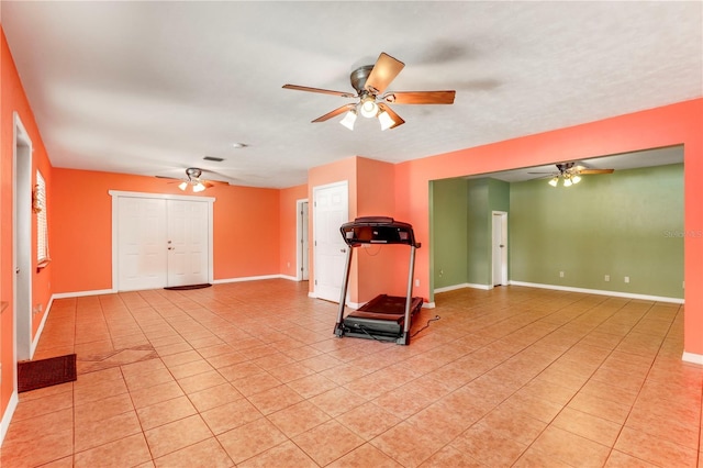 workout area with ceiling fan and light tile patterned floors