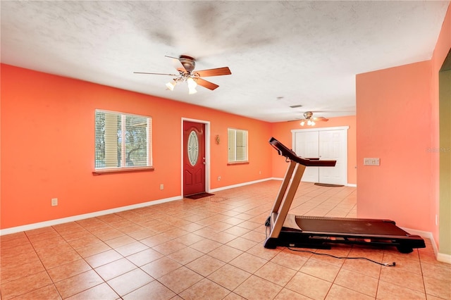 exercise room with light tile patterned flooring, ceiling fan, and a textured ceiling