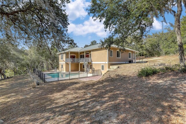 rear view of house featuring a fenced in pool, a balcony, and a patio area