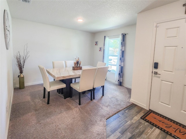 dining area featuring dark wood-type flooring and a textured ceiling