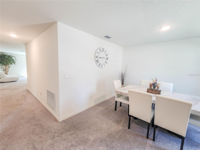 carpeted dining space with a textured ceiling