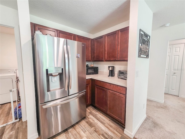 kitchen featuring stainless steel fridge with ice dispenser, washer / clothes dryer, a textured ceiling, and light wood-type flooring