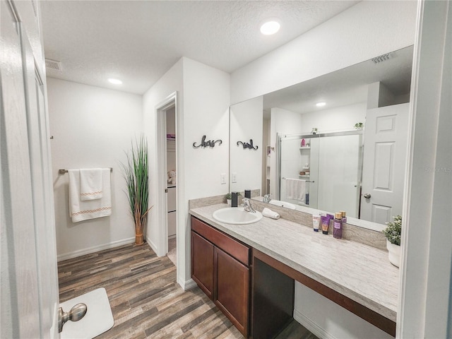 bathroom with walk in shower, vanity, hardwood / wood-style floors, and a textured ceiling