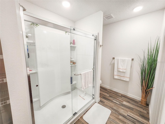 bathroom featuring hardwood / wood-style flooring, toilet, an enclosed shower, and a textured ceiling