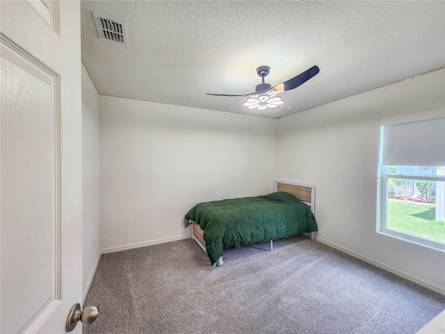 unfurnished bedroom featuring ceiling fan, a textured ceiling, and carpet flooring