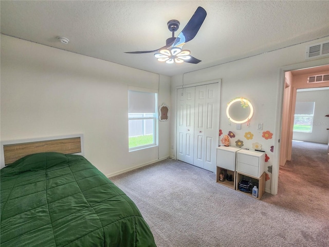 bedroom with ceiling fan, a closet, a textured ceiling, and carpet