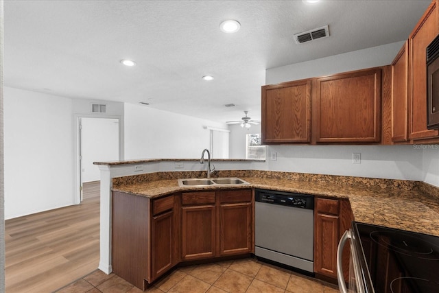 kitchen with sink, dark stone counters, light tile patterned floors, kitchen peninsula, and stainless steel appliances