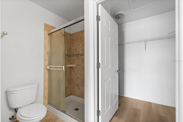 bathroom featuring toilet, a shower with shower door, and hardwood / wood-style floors