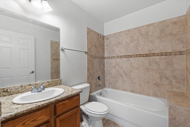 full bathroom featuring vanity, tiled shower / bath, and toilet