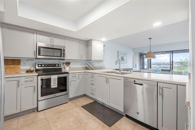 kitchen with sink, hanging light fixtures, appliances with stainless steel finishes, kitchen peninsula, and a raised ceiling