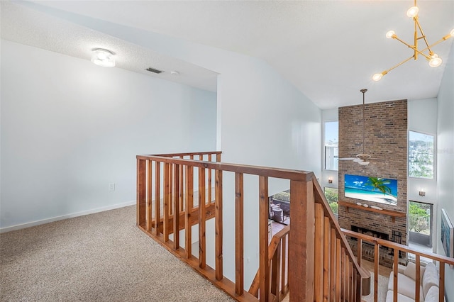 corridor with plenty of natural light, carpet floors, high vaulted ceiling, and a chandelier