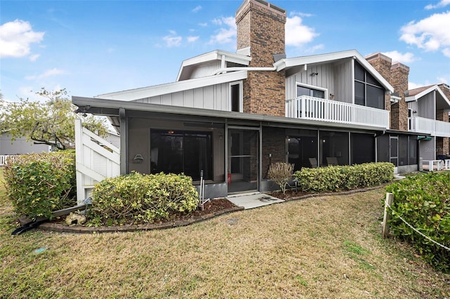 rear view of property with a yard, a sunroom, and a balcony