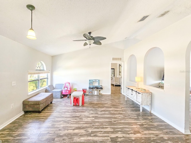 recreation room featuring ceiling fan, wood-type flooring, vaulted ceiling, and a textured ceiling