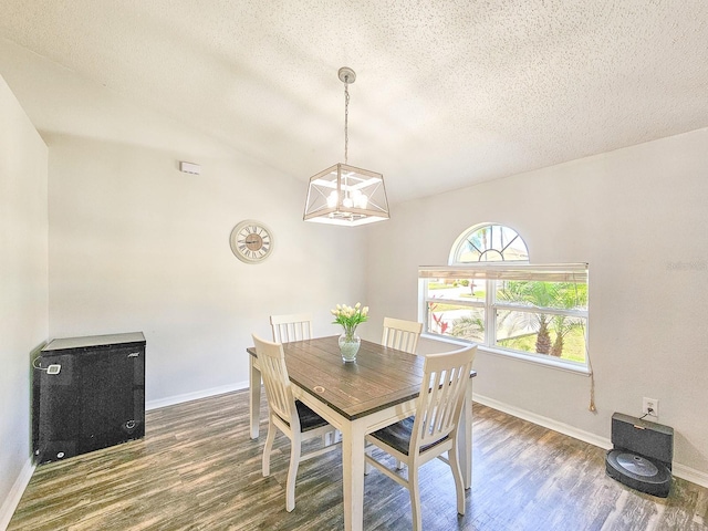 dining space with dark hardwood / wood-style flooring, a chandelier, vaulted ceiling, and a textured ceiling