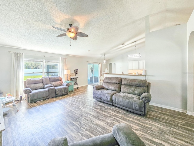 living room with ceiling fan, lofted ceiling, wood-type flooring, and a textured ceiling