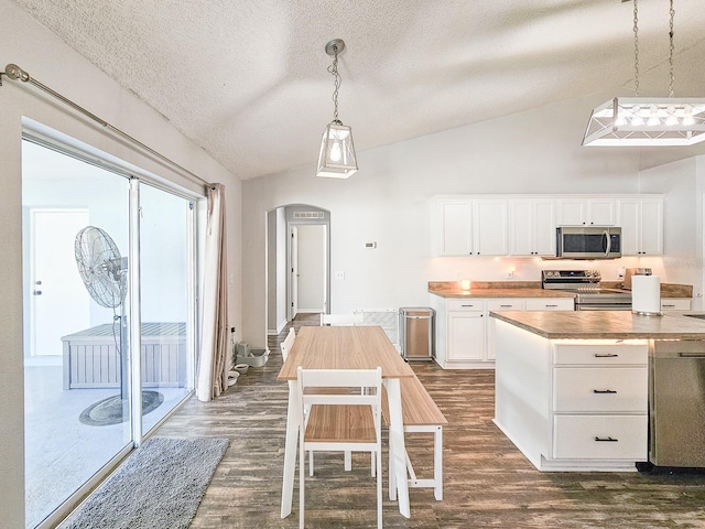 kitchen with wood counters, hanging light fixtures, stainless steel appliances, and white cabinets