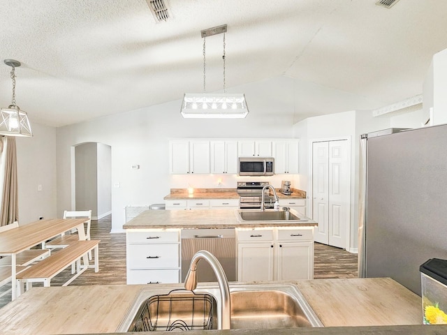 kitchen featuring appliances with stainless steel finishes, pendant lighting, an island with sink, sink, and white cabinets