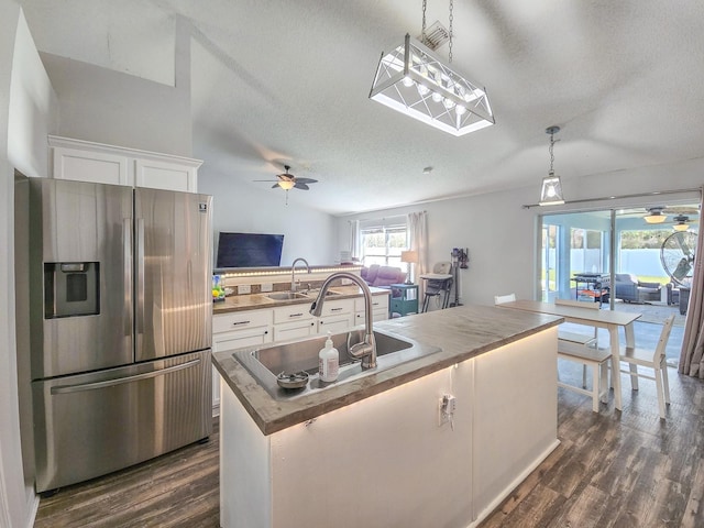 kitchen with a kitchen island, white cabinetry, stainless steel fridge, hanging light fixtures, and dark wood-type flooring