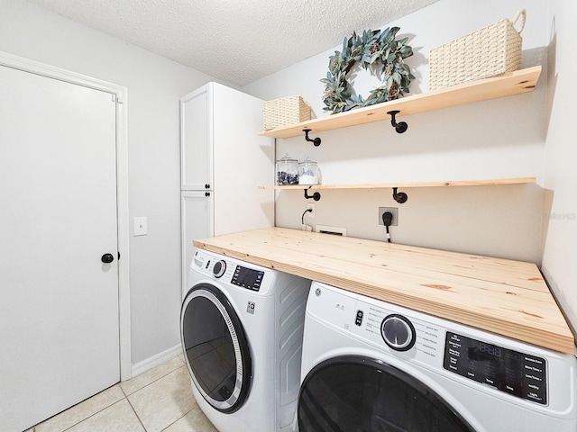 laundry room with cabinets, light tile patterned flooring, a textured ceiling, and independent washer and dryer