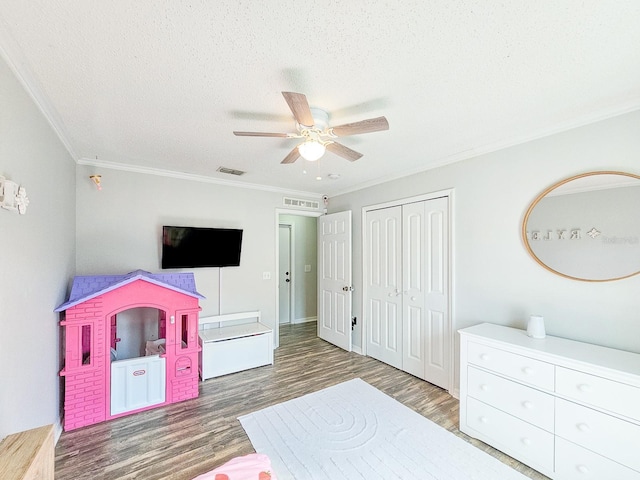 bedroom featuring ceiling fan, crown molding, dark wood-type flooring, a textured ceiling, and a closet