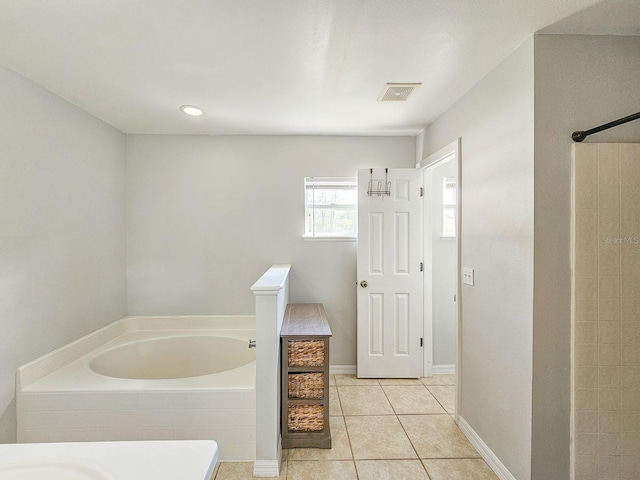 bathroom with a relaxing tiled tub and tile patterned floors