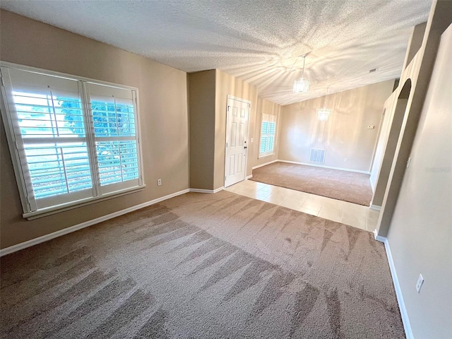 carpeted empty room with vaulted ceiling and a textured ceiling