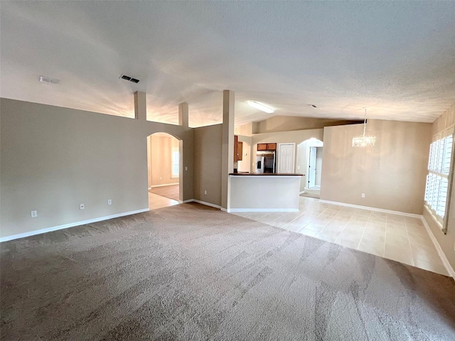 unfurnished living room with light colored carpet, lofted ceiling, a chandelier, and a textured ceiling