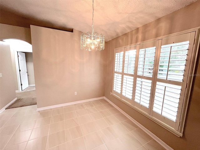 spare room with light tile patterned floors, a chandelier, and a textured ceiling