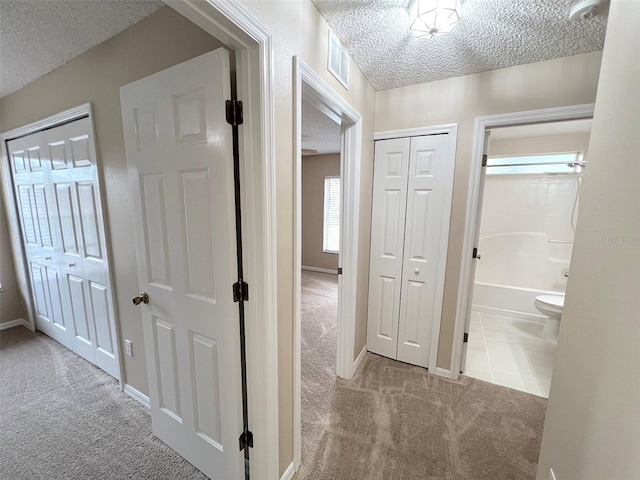 hall with light carpet and a textured ceiling