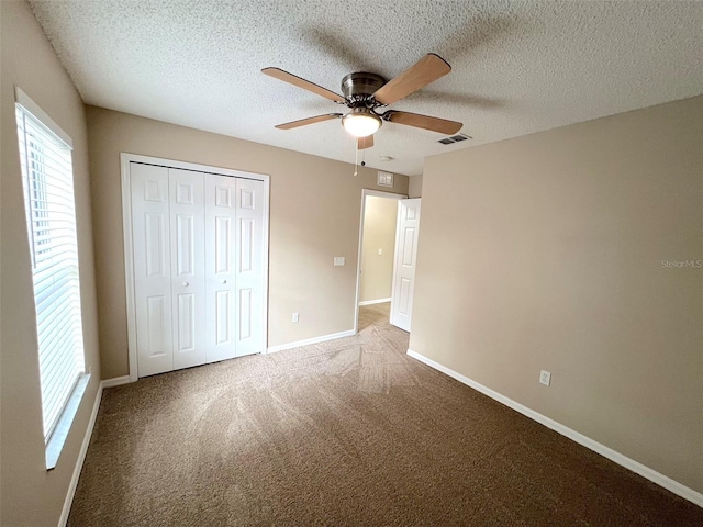 unfurnished bedroom featuring ceiling fan, carpet flooring, a textured ceiling, and a closet