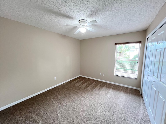 carpeted spare room featuring a textured ceiling and ceiling fan