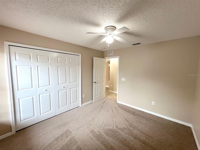 unfurnished bedroom with carpet floors, a textured ceiling, ceiling fan, and a closet