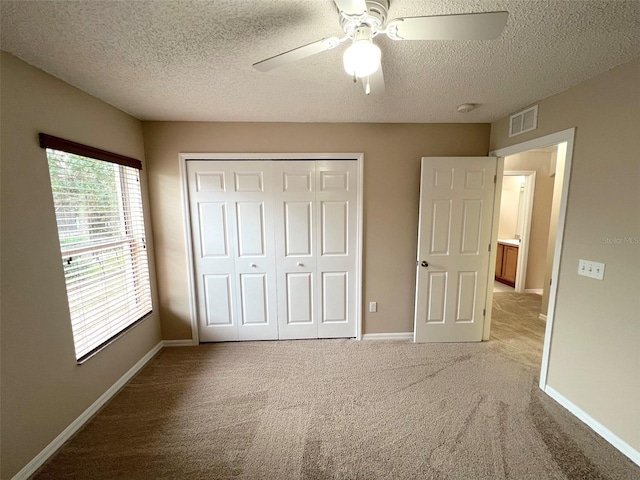 unfurnished bedroom with ceiling fan, carpet floors, a closet, and a textured ceiling