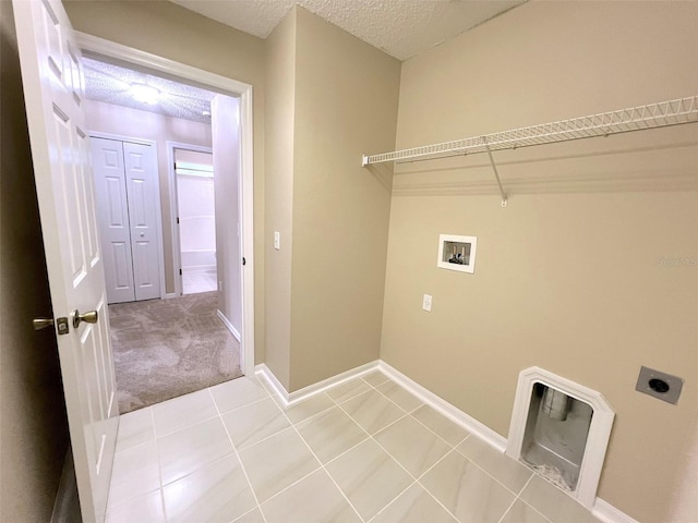 laundry room featuring electric dryer hookup, tile patterned flooring, hookup for a washing machine, and a textured ceiling