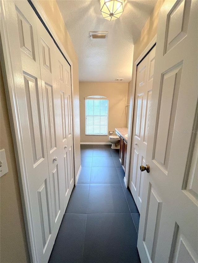 corridor with a textured ceiling and dark tile patterned floors