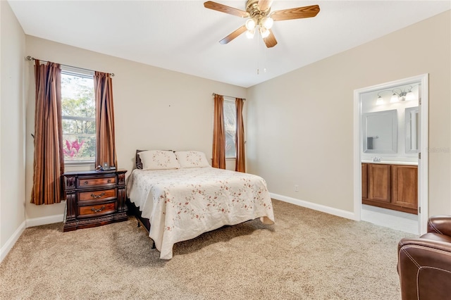 bedroom featuring ceiling fan, light colored carpet, and ensuite bath