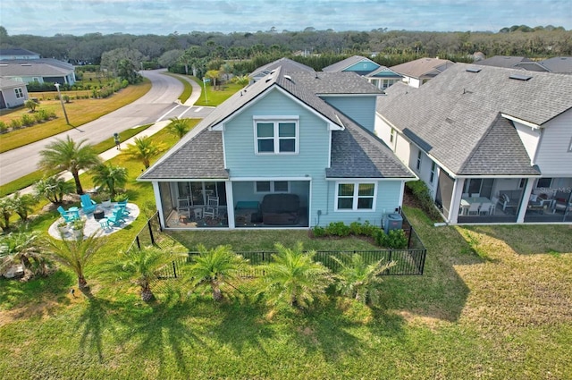 rear view of house with a shingled roof, a residential view, a fenced backyard, and a sunroom