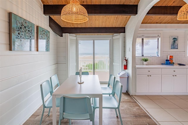 dining area featuring wood ceiling, light wood-style flooring, and beam ceiling