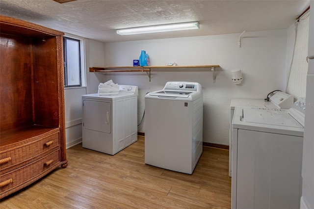 laundry area with laundry area, a textured ceiling, light wood finished floors, and separate washer and dryer