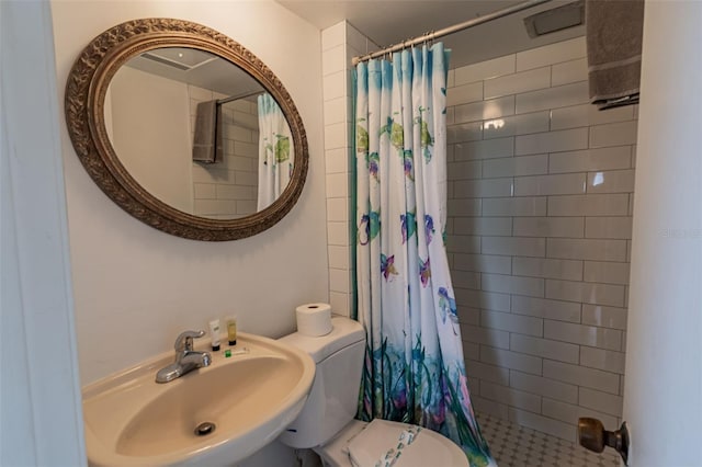 bathroom featuring tiled shower, a sink, and toilet