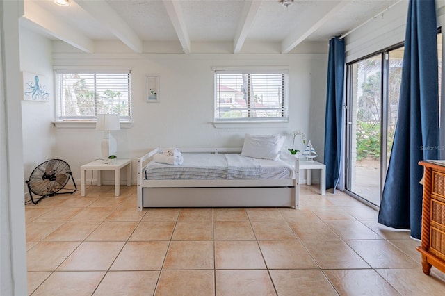 bedroom with a textured ceiling, beamed ceiling, light tile patterned flooring, and access to exterior