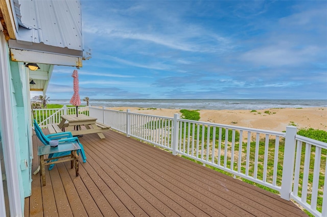 wooden terrace featuring a water view and a beach view