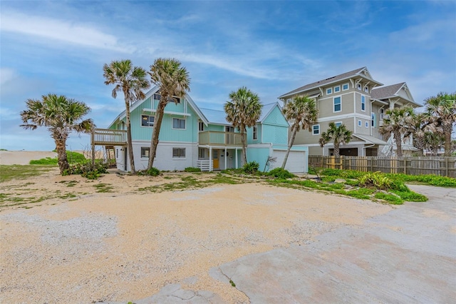 beach home with a balcony, driveway, a garage, and fence