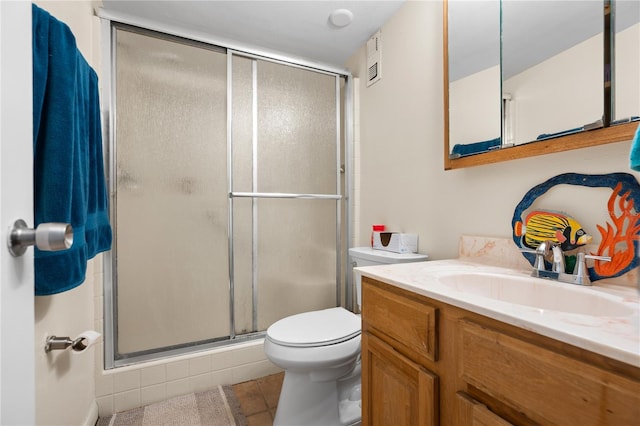 bathroom featuring tile patterned flooring, vanity, toilet, and a shower with shower door