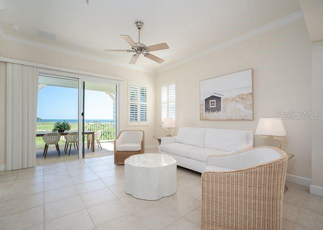 tiled living room with crown molding and ceiling fan