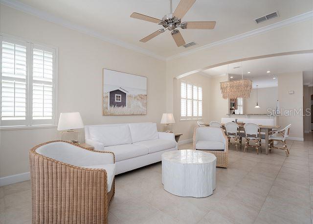 tiled living room with ornamental molding, a wealth of natural light, and ceiling fan