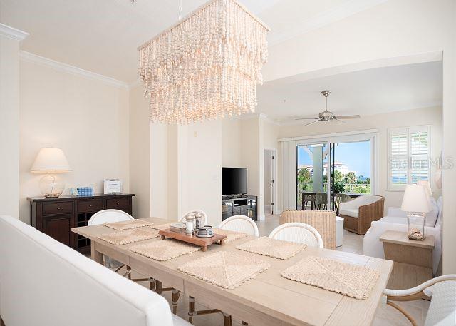 dining space with crown molding and ceiling fan with notable chandelier